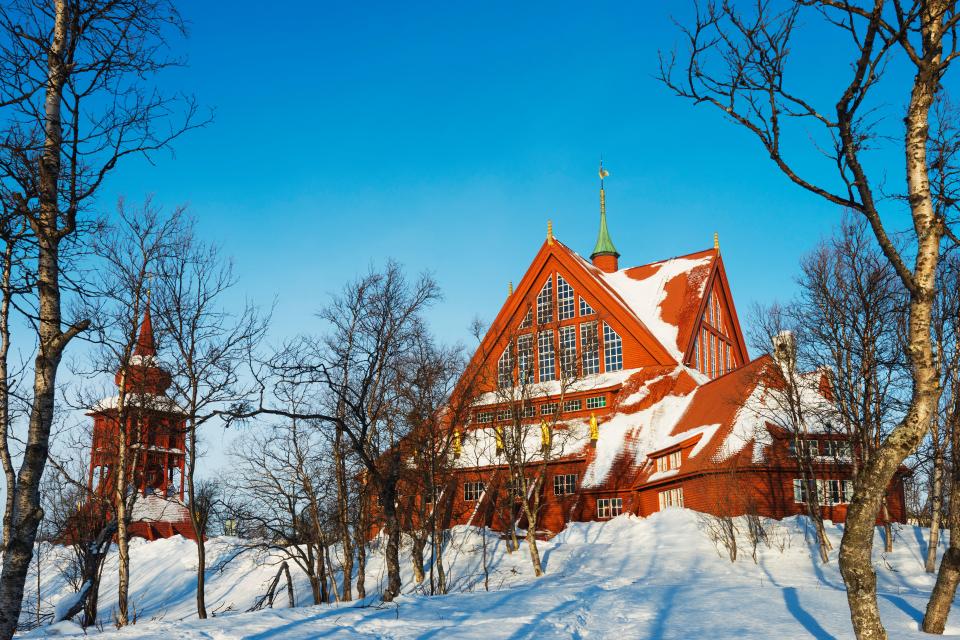 a red building with a green roof is surrounded by snow and trees