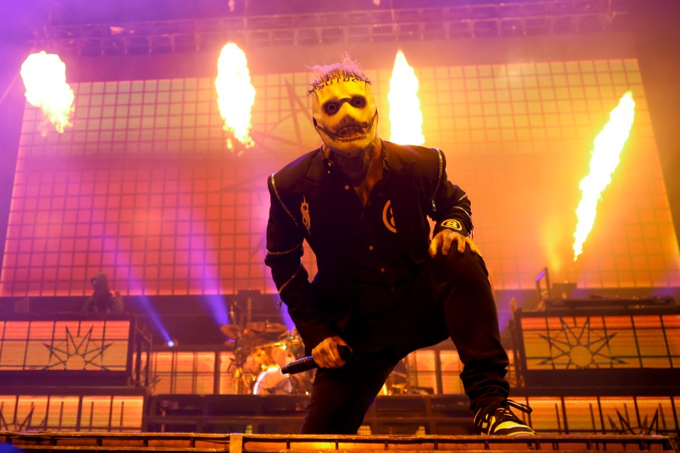 a man in a mask holds a microphone in front of flames