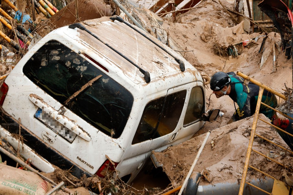 Civil Guard officers search for survivors inside cars trapped under the foundations of a building under construction in the town of Paiporta