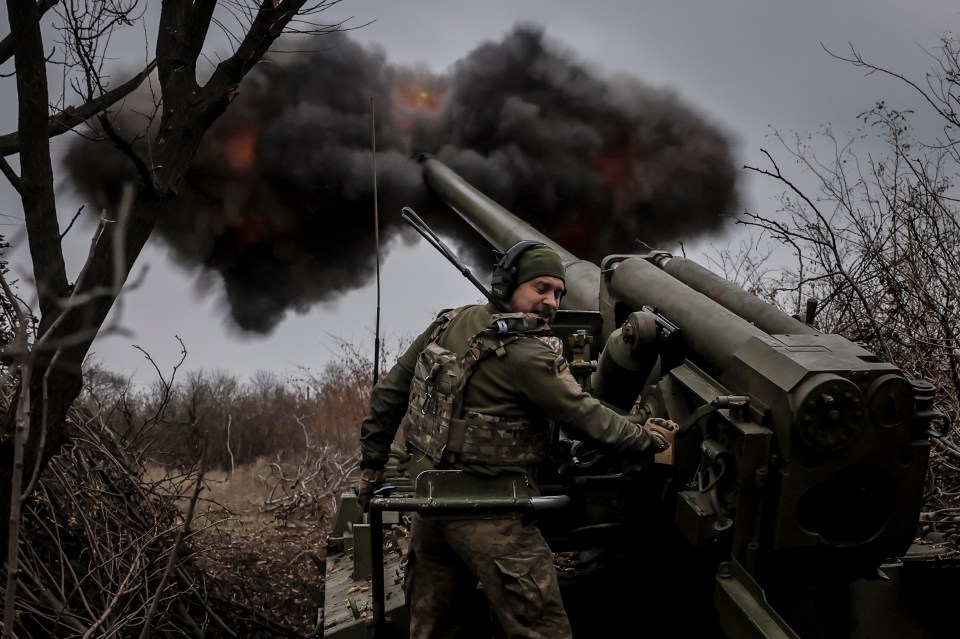 a man in a military uniform stands in front of a cannon with smoke coming out of it