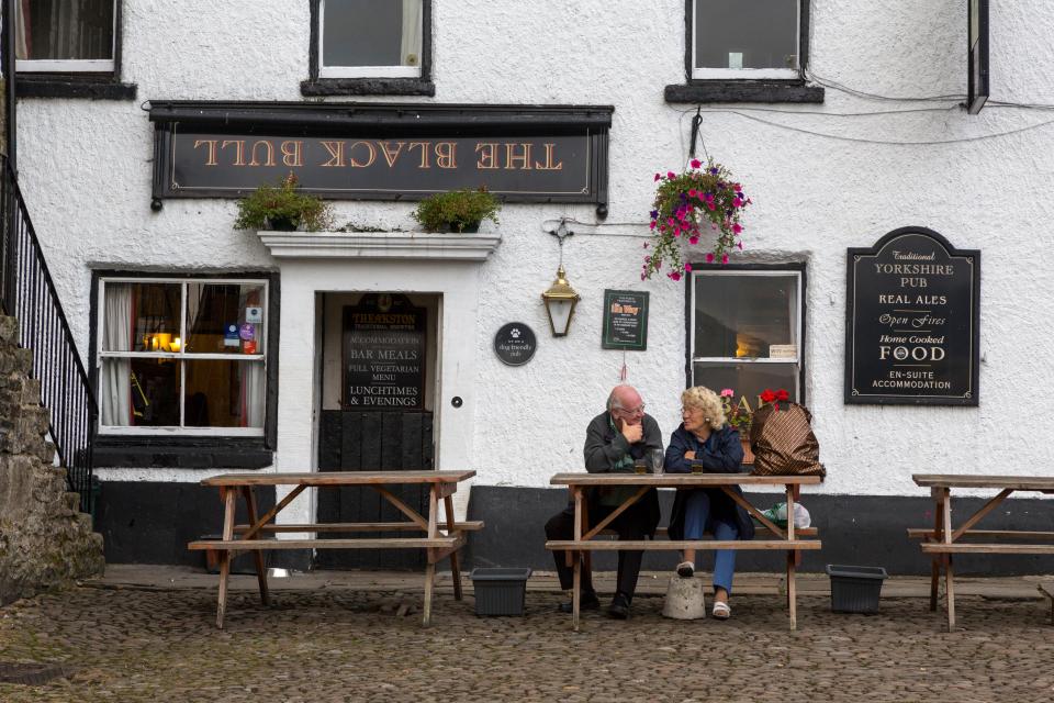 two people sit at a picnic table outside the black bull