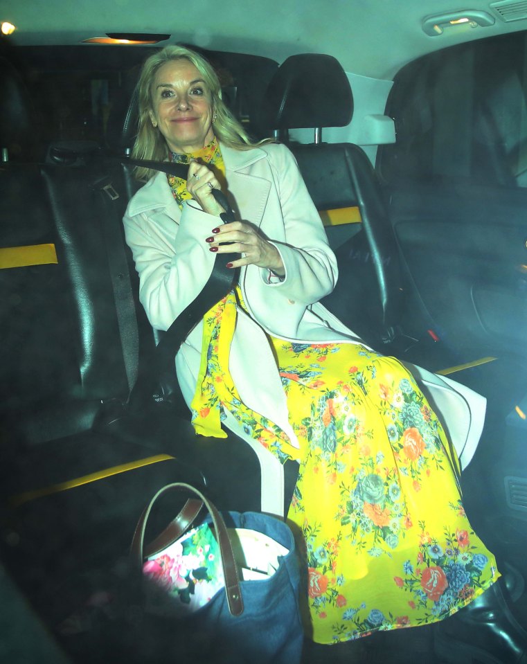 a woman in a yellow floral dress is sitting in the back seat of a car