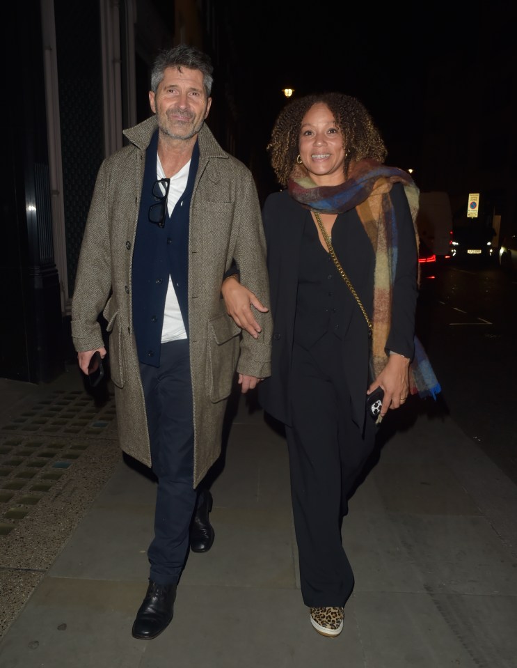 a man and a woman are walking down a sidewalk at night