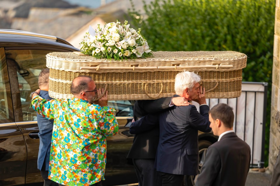 a man in a colorful shirt is carrying a coffin