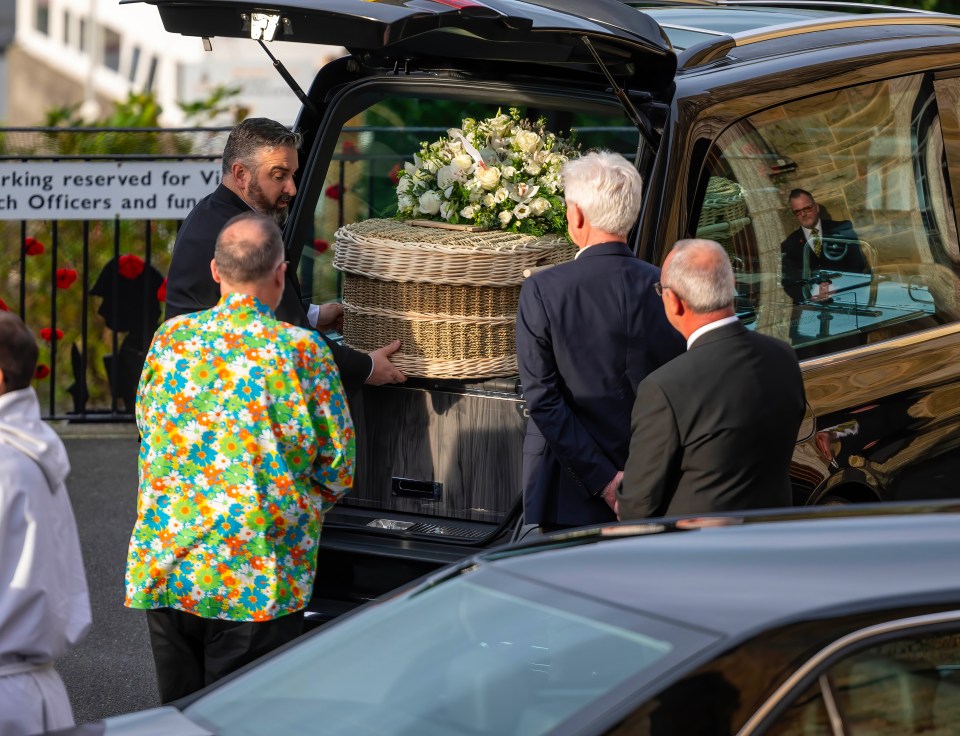 a wicker coffin is being loaded into the back of a car