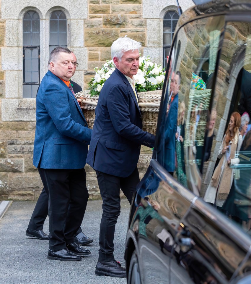 a man is carrying a basket of flowers into a car