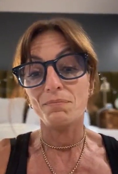 a woman wearing glasses and a choker is making a funny face .