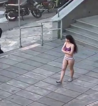 a woman in a bikini is walking down a sidewalk