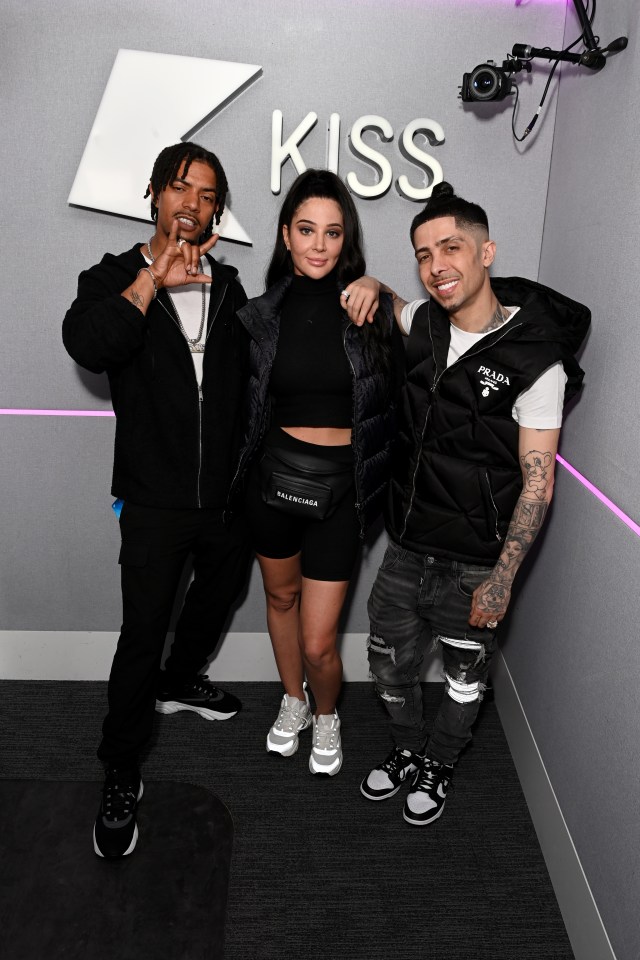 three people pose for a picture in front of a kiss sign