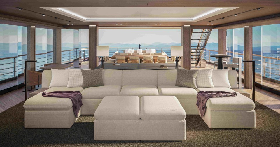 a living room with a couch and ottomans with a view of the ocean