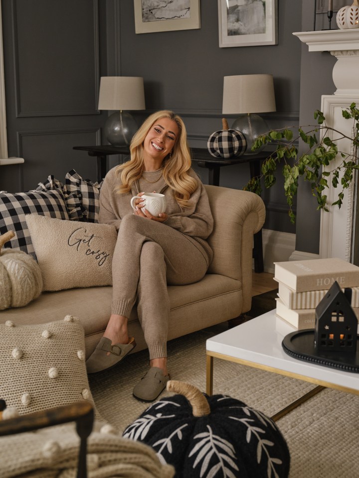 a woman sits on a couch holding a cup of coffee