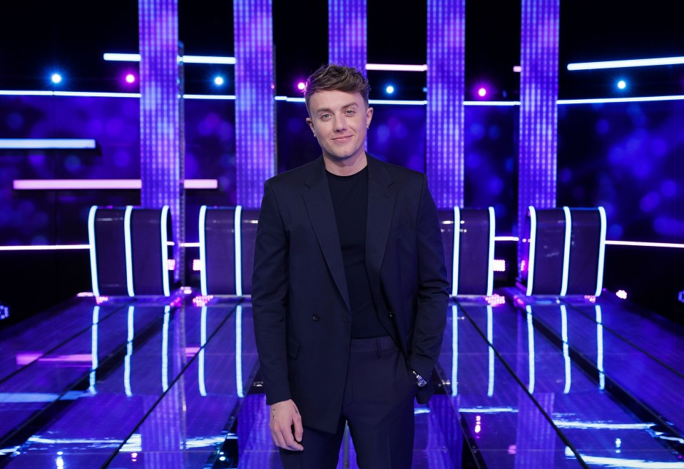 a man in a suit stands in front of purple lights