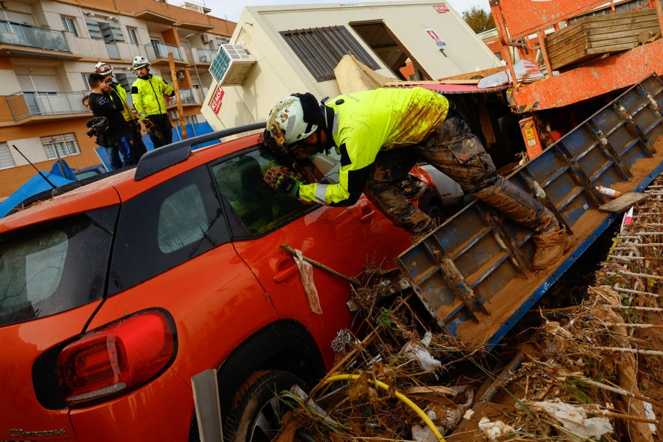 A firefighter looks inside a car after heavy rains in Alfafar, Valencia