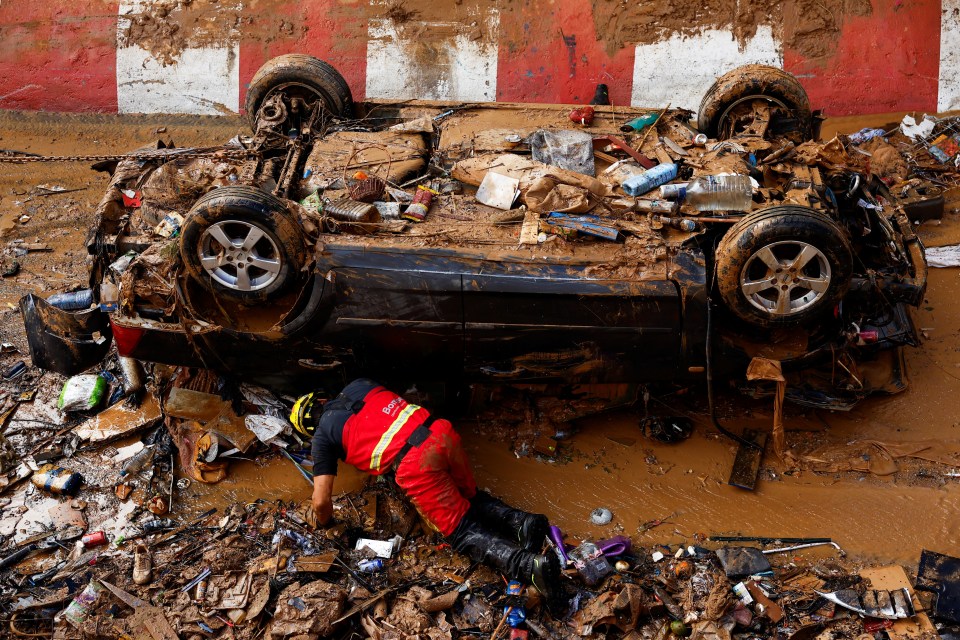 A firefighter searches for victims in a damaged car