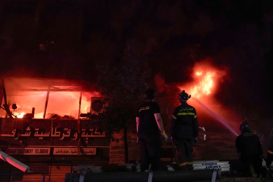 Firefighters extinguish a fire inside a computer shop hit during an Israeli airstrike in central Beirut, on Sunday