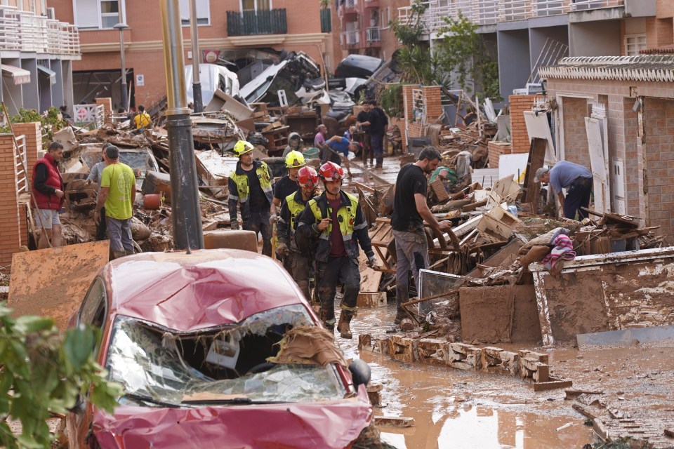 a group of people walking through a flooded area with a sign that says no parking