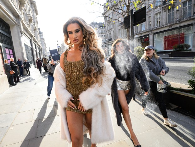 a woman in a fur coat is spraying another woman with a bucket that says adidas on it