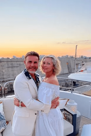 a man and a woman are posing for a picture on a yacht .