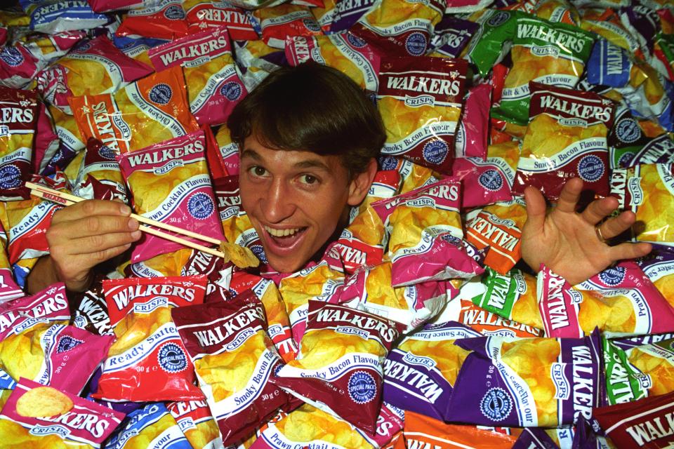 a man is surrounded by bags of walkers chips