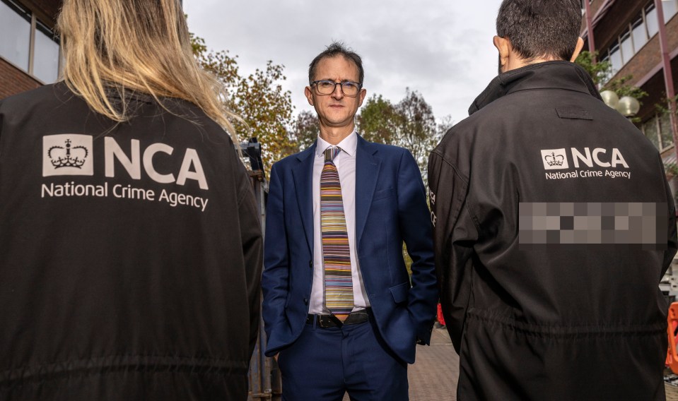 a man in a suit stands in front of two people wearing jackets that say nca