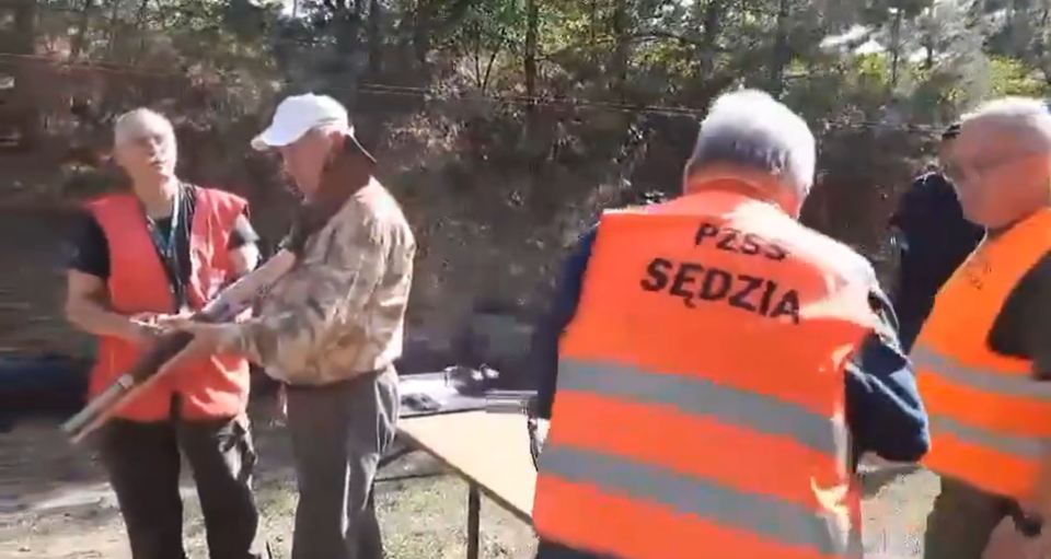 Moments before the gun fires, the judge points the firearm directly at two bystanders