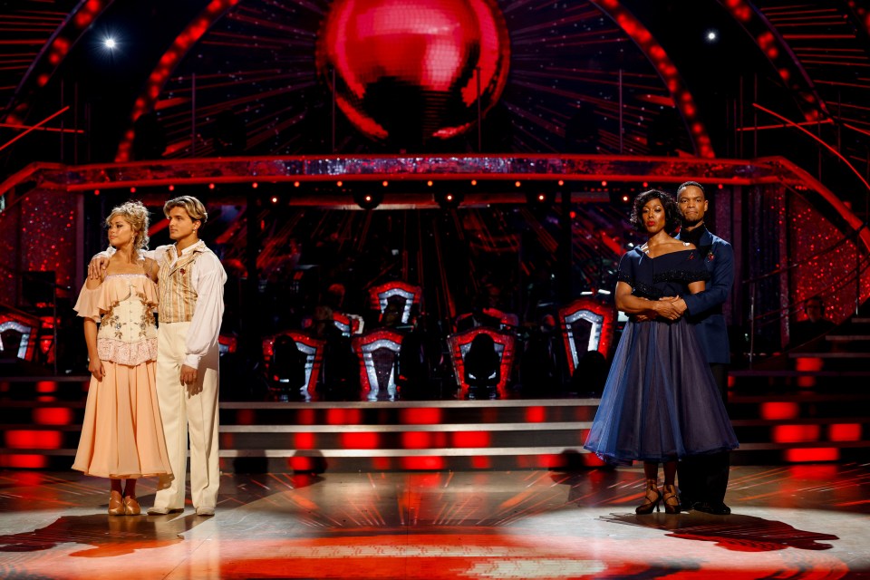 a couple of people standing on a stage with a red ball in the background