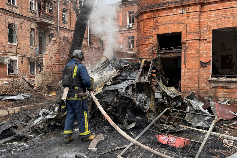 Rescue workers extinguish a burned-out car at the site of a Russian missile strike on the city's Kyivskyi district