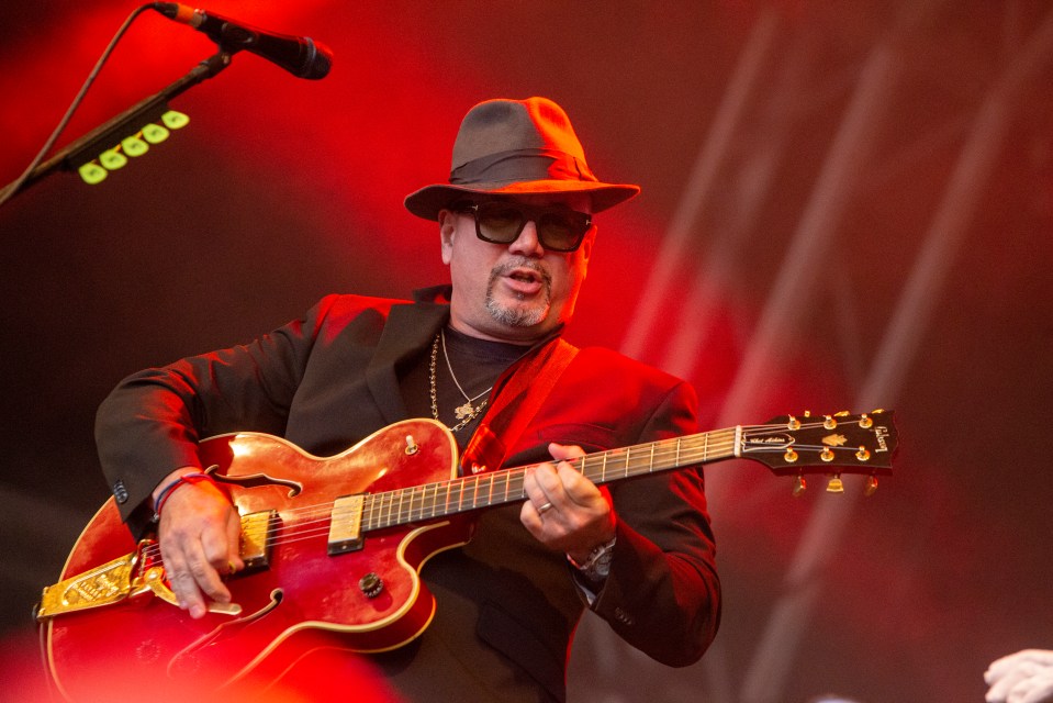 a man playing a gibson guitar in front of a microphone