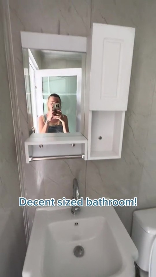 a woman taking a picture of herself in a bathroom mirror with the caption decent sized bathroom