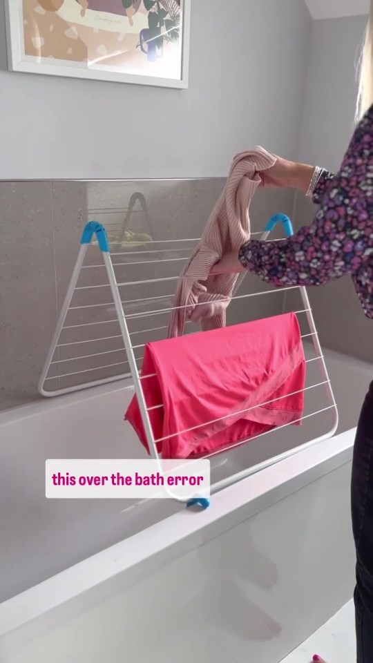 a woman hangs a pink shirt on a drying rack over a bathtub