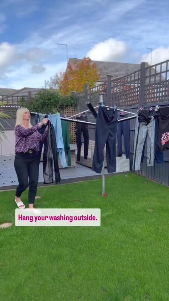 a woman hangs clothes outside on a clothes line