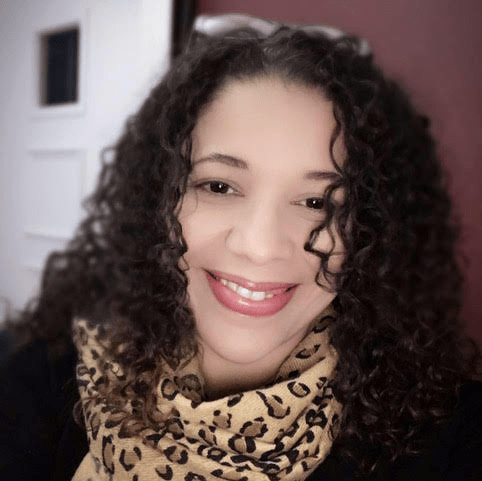 a woman with curly hair wearing a leopard print scarf