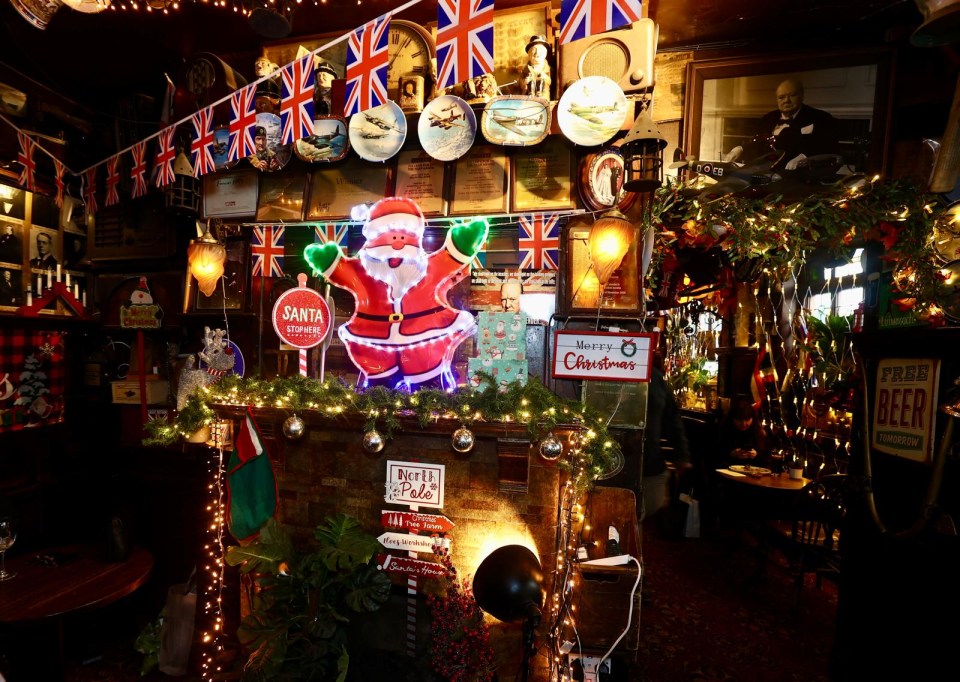 A Christmas scene in a pub decorated with lights, garland, and a Santa figure.