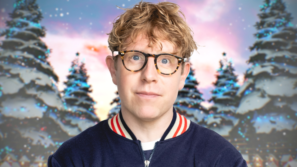 a man wearing glasses stands in front of a snowy forest