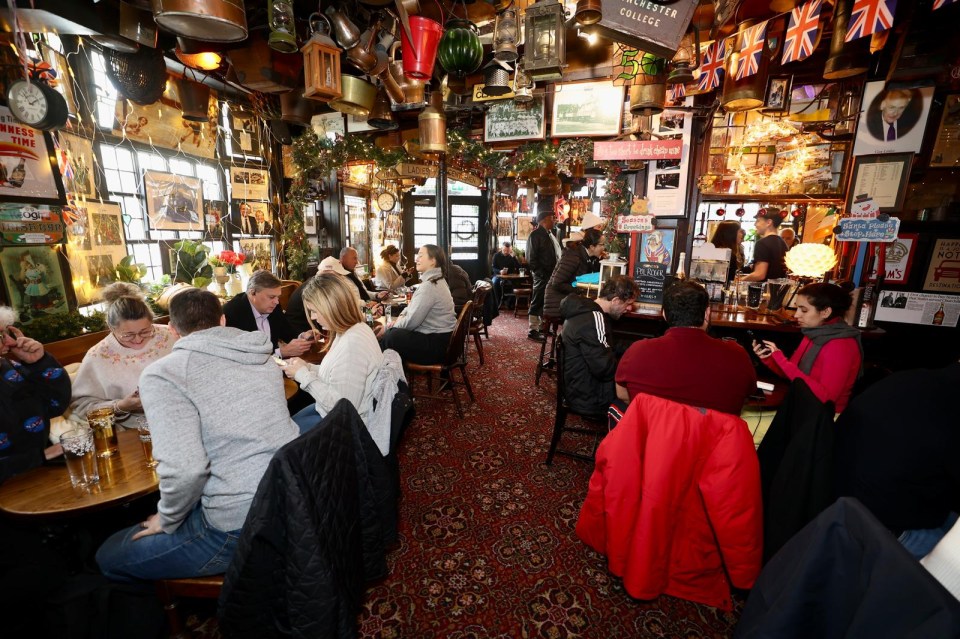 Crowded pub interior with patrons seated at tables.