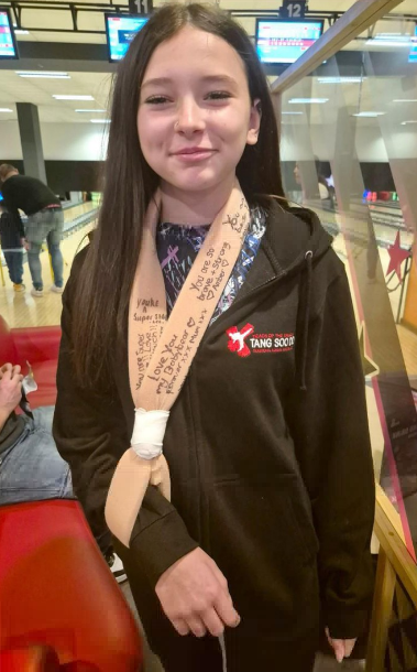 a young girl wearing a tang soo do hoodie stands in a bowling alley