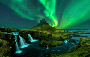 a waterfall in front of a mountain with the aurora borealis behind it