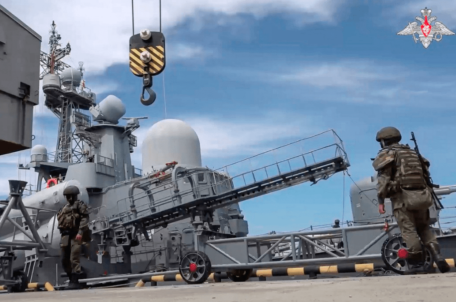 two soldiers stand on the deck of a military ship