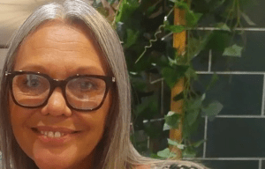 a woman with gray hair and glasses is smiling for the camera .