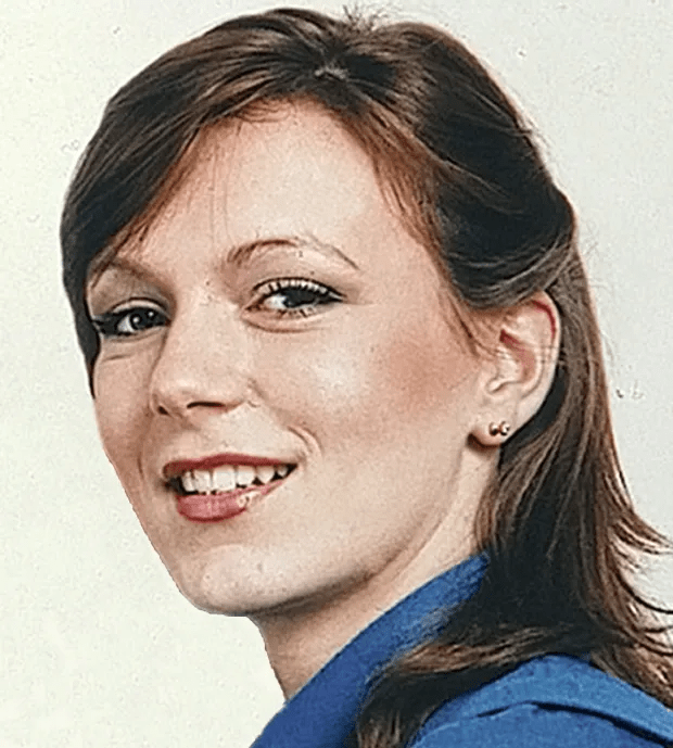 a woman in a blue shirt smiles for the camera