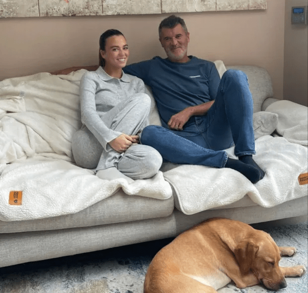 a man and a woman sit on a couch with a dog