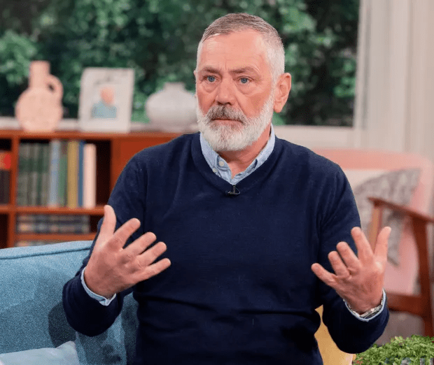 a man with a beard is sitting in a chair with his hands outstretched