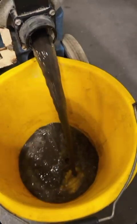 a yellow bucket filled with dirty water is being poured into it .