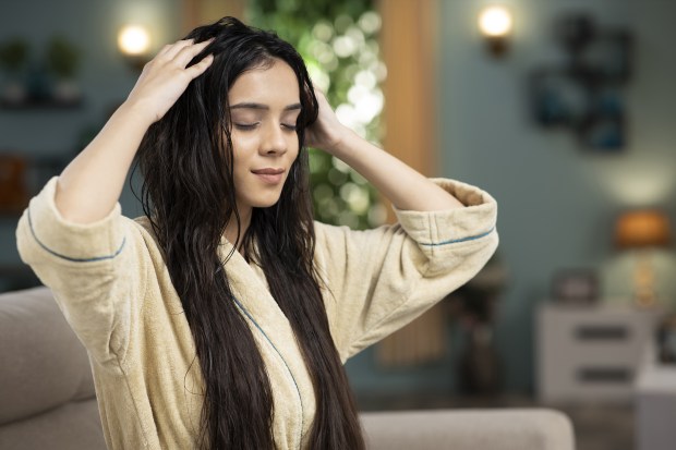 a woman in a bathrobe is touching her hair