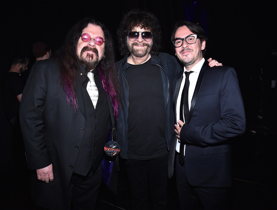 three men are posing for a picture and one of them has a badge that says ' heavy metal ' on it