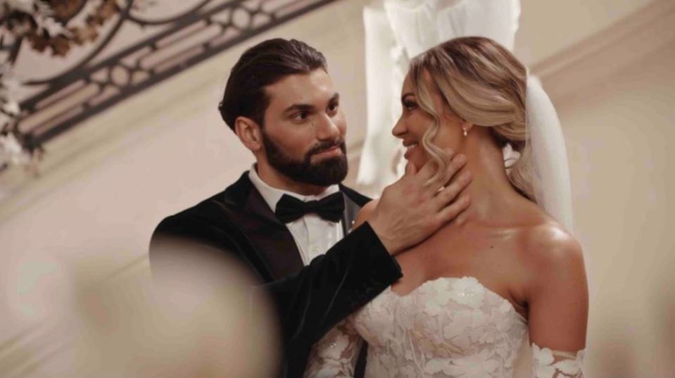 a bride and groom are posing for a picture and the groom is touching the bride 's neck