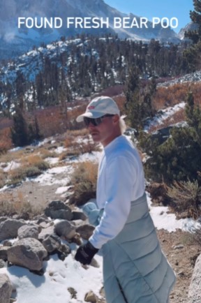 a man standing in the snow with the words found fresh bear poo above him