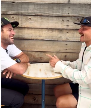 two men are sitting at a table and laughing