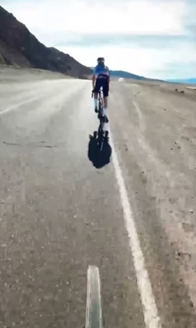 a man is riding a bike down a desert road .