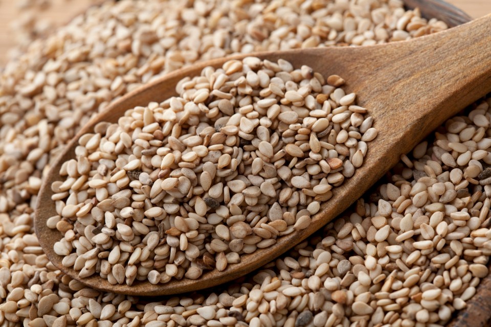 a wooden spoon is filled with sesame seeds